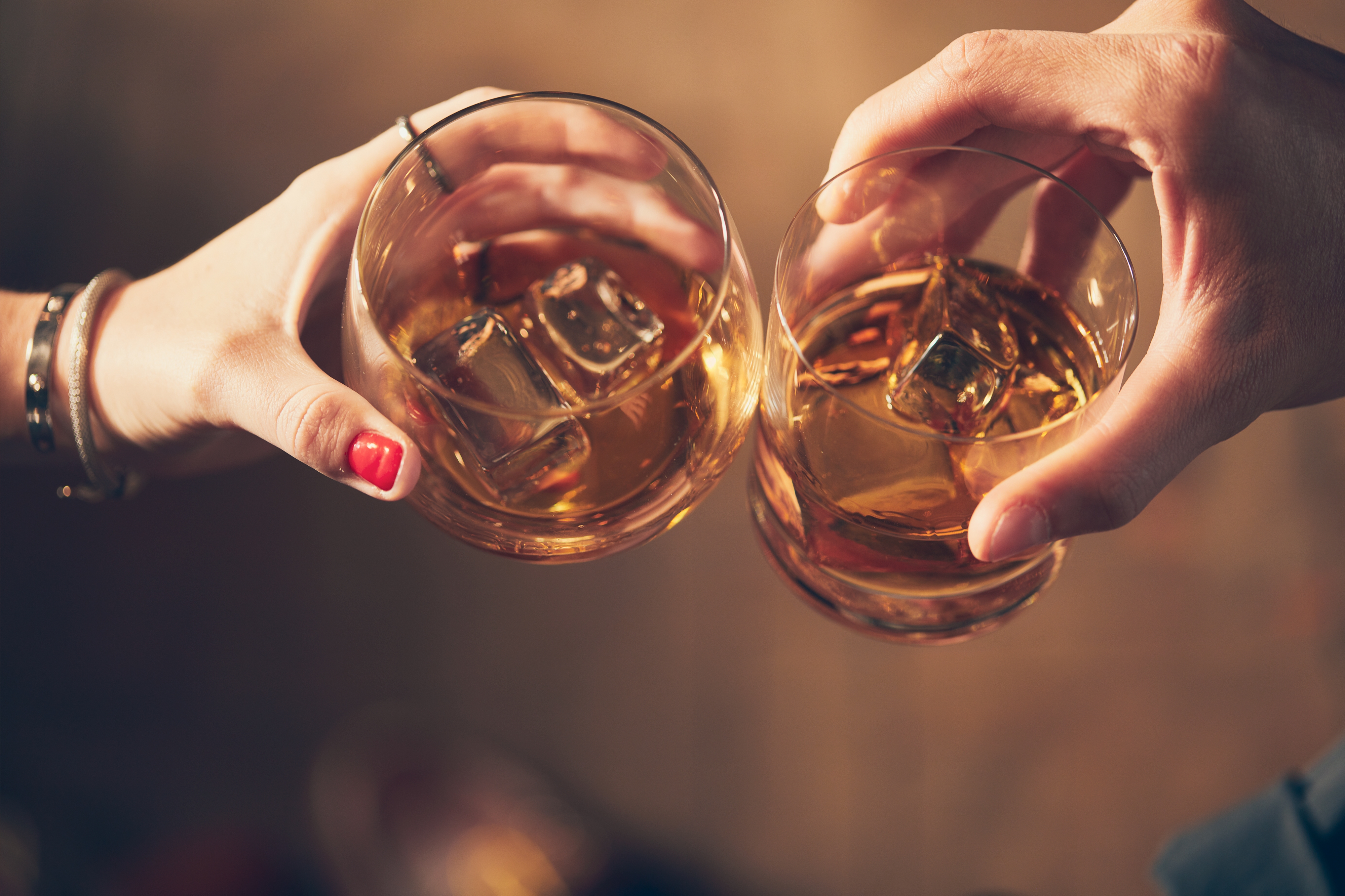 closeup-shot-two-people-clinking-glasses-with-alcohol-toast